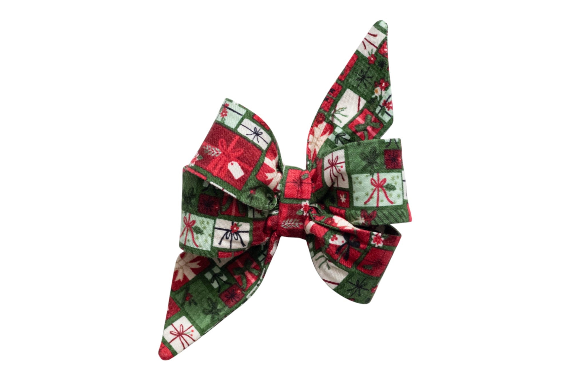 Oversized dog belle bow made from festive holiday fabric patterned with a grid of gift boxes, each tied with colorful bows and accented with holly and gift tags. The belle bow features wide, layered loops and long, pointed tails for a dramatic look, with a cinched center for structure.