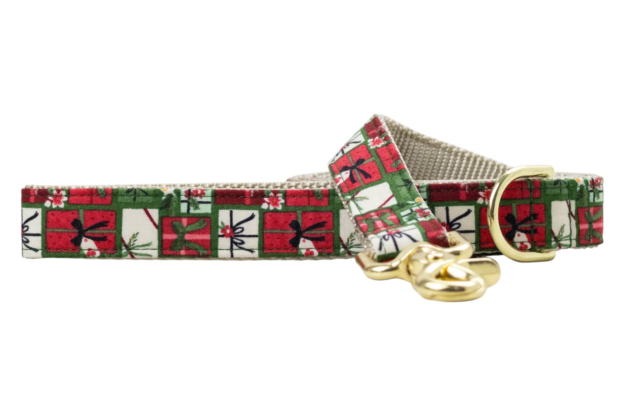 Holiday-themed dog leash featuring a repeating print of square gift boxes in classic Christmas colors. Each box is detailed with ribbons, tags, holly, or pine accents, creating a tightly packed pattern. The leash is backed with nylon webbing and includes metal hardware.