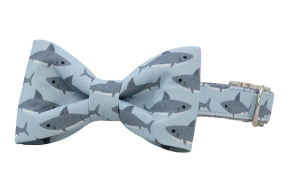 Light blue dog bow tie collar featuring a repeating gray shark pattern, attached to a matching adjustable collar with a metal D-ring