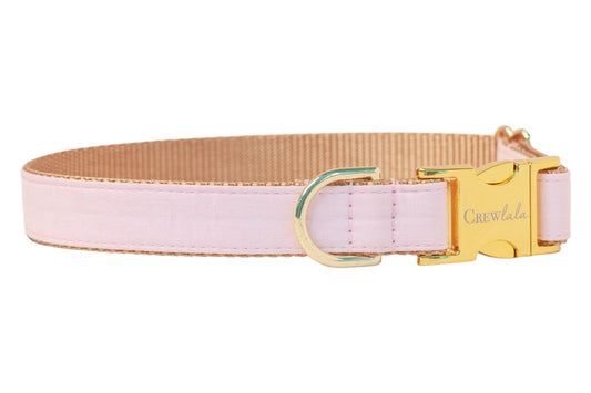 Dog collar made from solid light pink fabric, layered over nylon webbing. Features a gold-tone side-release buckle engraved with “Crewlala,” a matching D-ring for leash attachment, and neatly stitched edges for a clean, polished finish.