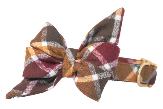 Adjustable dog collar with an oversized belle bow in warm fall hues, crafted from soft flannel and featuring two large pointed tails, attached to a matching collar with metal hardware.