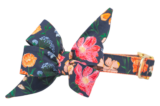 Floral belle bow dog collar with a bold navy blue base and a mix of bright flowers. The large matching belle bow has extended points for a stylish, feminine statement, and the collar features a shiny buckle and D-ring.