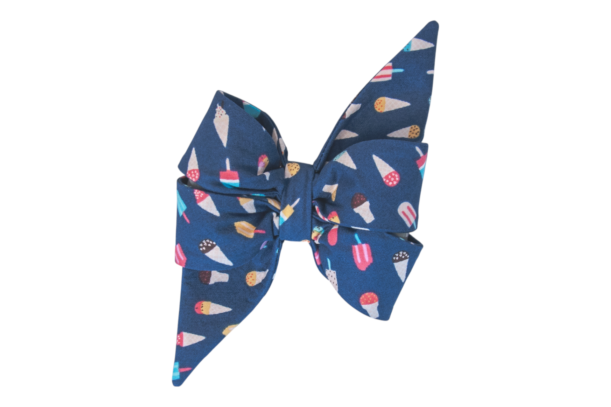 A navy blue dog bow made of soft fabric, shaped with two large loops and pointed tails. The bow is covered in a playful pattern of various frozen treats, including ice cream cones and popsicles in vibrant colors like red, pink, yellow, and white, giving it a fun, summer-themed vibe.