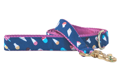 Stylish dog leash with a whimsical ice cream  and popsicle print on a blue fabric exterior and contrasting pink woven backing. The leash includes a brass-colored swivel clasp and metal D-ring, suggesting high-quality construction and fun summer vibes.