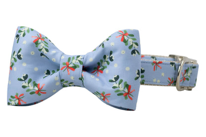 Holiday dog collar and bow tie set with a cheerful mistletoe print on soft blue fabric. The bow tie is centered on the collar and features the same festive foliage pattern. Finished with sleek hardware.