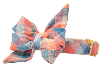 Close-up of a dog collar with a voluminous plaid bow in muted fall tones, crafted from soft flannel. The belle bow has two tall, pointed loops and two shorter angled loops for a layered effect. The matching plaid-covered collar includes an adjustable metal buckle and d-ring.