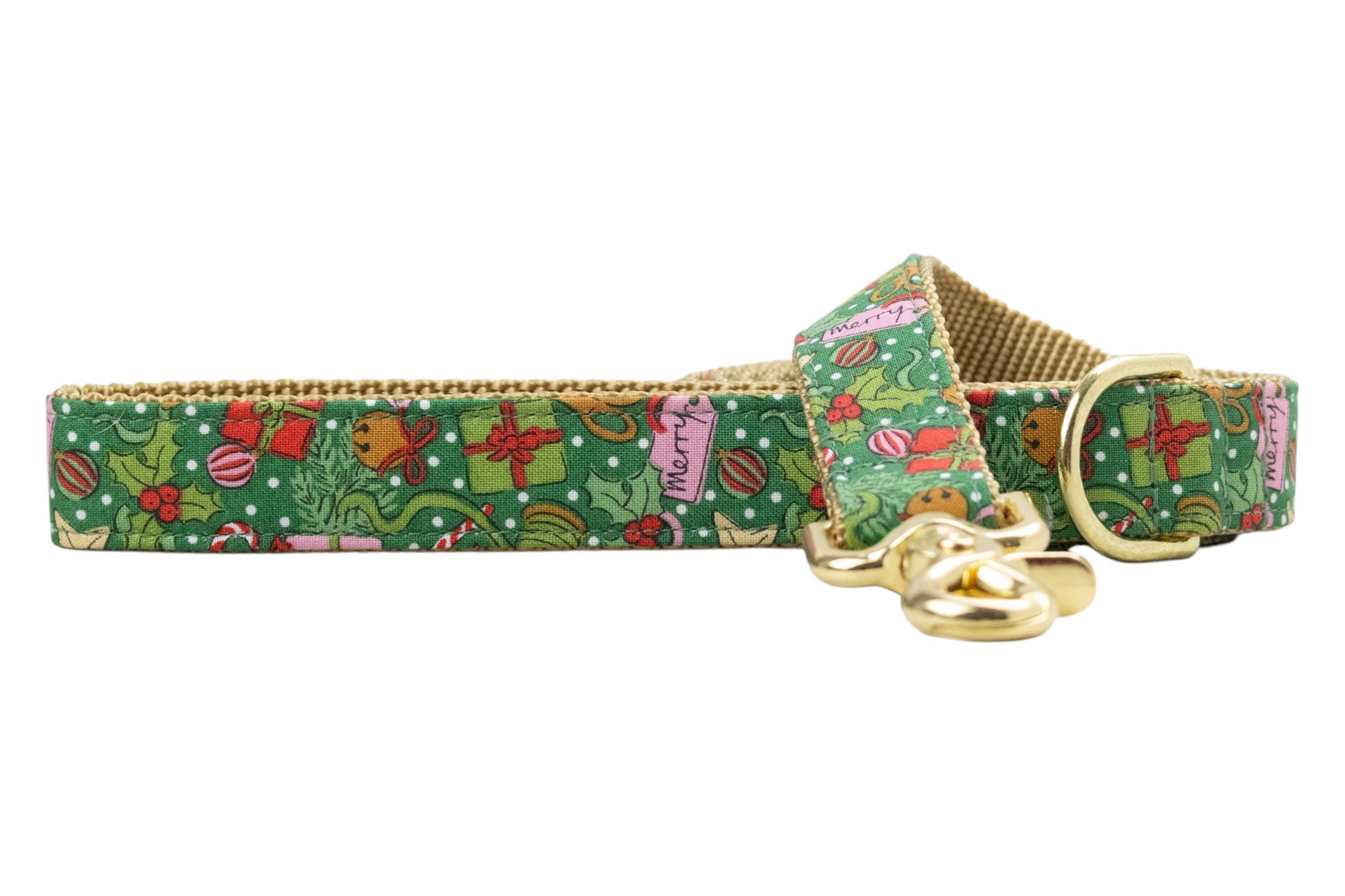 Festive green dog leash decorated with small holiday icons including presents, holly, candy canes, bells, and ornaments, over a dotted background. Nylon webbing underside and hardware add a warm seasonal touch.