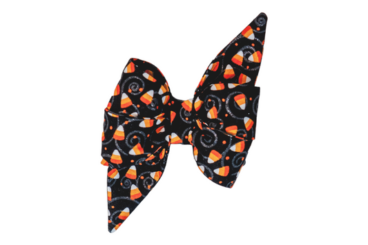 Oversized dog belle bow featuring a candy corn print with swirly accents on a black background. The layered design with long, pointed ends makes it a standout accessory for Halloween costumes or festive fall outings.
