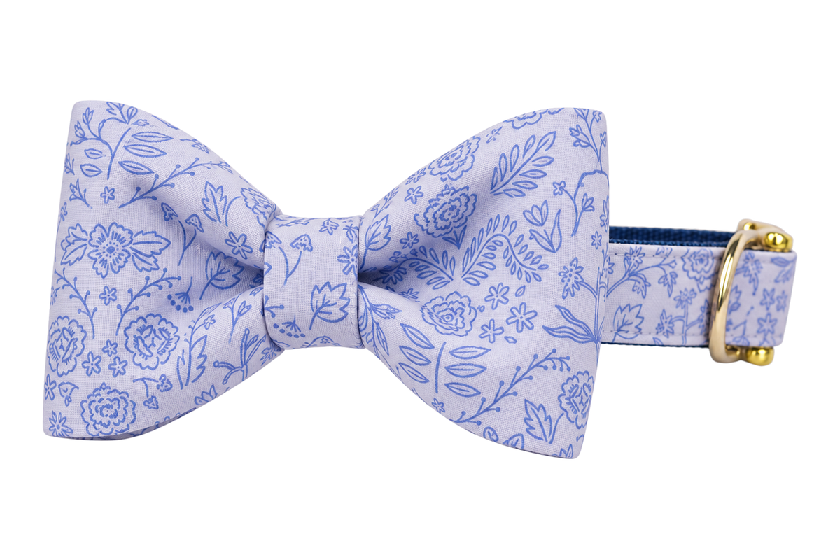 Classic dog collar featuring a Twilight Stems fabric bow tie, a pale lavender fabric with a periwinkle blue toile of roses and leafy stems, attached to a matching Twilight Stems collar with a nylon inner lining and gleaming gold hardware, including a D-ring and buckle.