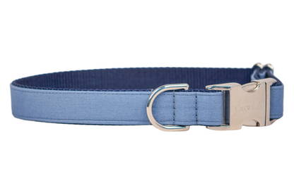 A slate blue dog collar made from ribbed fabric with a navy blue webbing interior. The collar features polished silver-tone hardware, including a D-ring and a side-release buckle engraved with the brand name "Crew LaLa." It has clean stitching and an adjustable fit for comfort and durability.