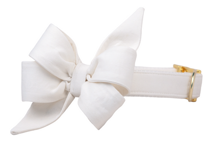 Elegant white dog collar with an attached oversized, sculptural bow and shiny gold-tone hardware, designed for formal occasions or bridal looks.
