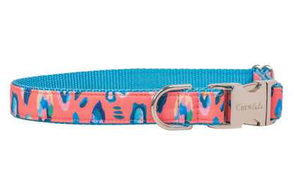 A modern dog collar with a coral base and multicolored leopard-style print, accented by bright webbing and polished hardware for a fierce but fun finish.