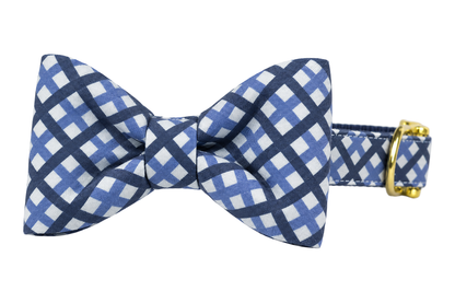 Classic dog collar featuring a Windowpane Plaid fabric bow tie, a navy and periwinkle blue lattice check on white, attached to a matching Windowpane Plaid collar with a nylon inner lining and gleaming gold hardware, including a D-ring and buckle.