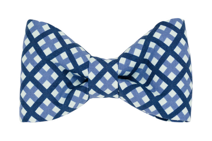 A handmade dog bow tie featuring a classic windowpane plaid pattern in shades of blue.