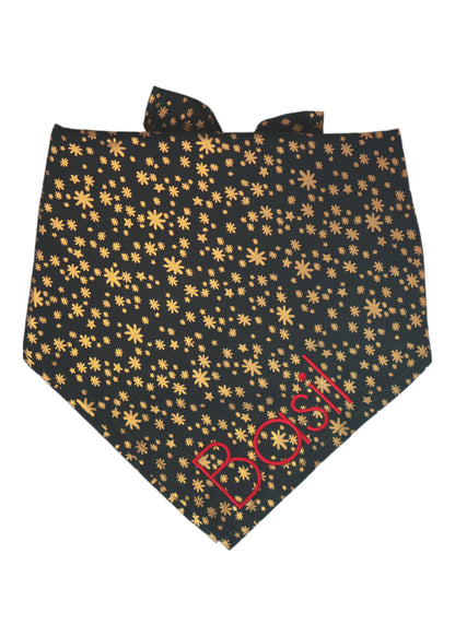 Dog bandana made of dark green fabric featuring an all-over metallic print of stars and starbursts in various sizes. The bandana is folded and tied at the top, combining a festive shimmer with a classic fold perfect for holiday celebrations or special events. The name "Basil" is embroidered on the bottom right.
