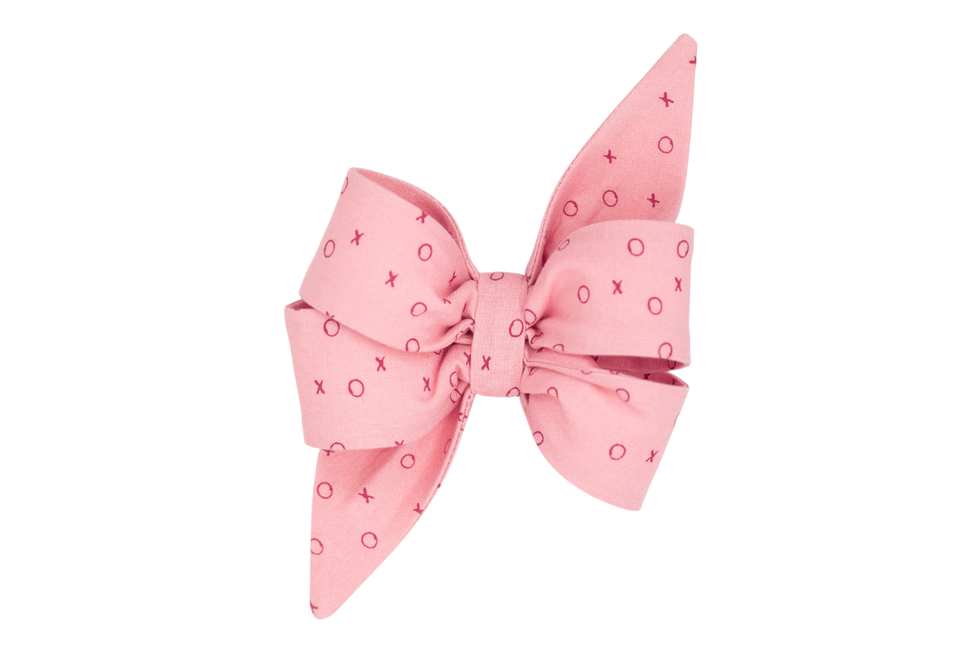 A handmade girl dog belle bow in a playful blush pink with a charming XO pattern in bright red, perfect for spreading love and cheer on Valentine's Day.