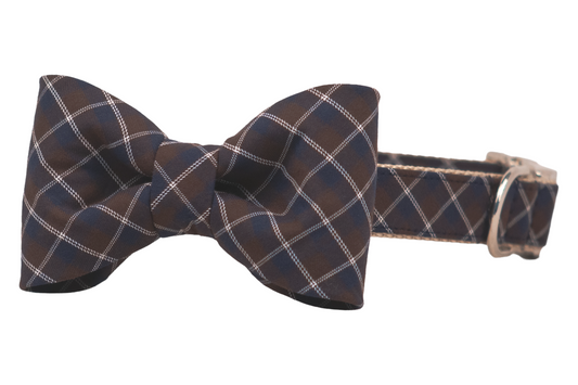 Classic bow tie dog collar made from soft fabric with a navy blue and brown diamond plaid design. The centered bow tie is neatly shaped and attached to a coordinating collar polished metal hardware.