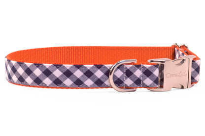 A classic dog collar in navy-and-white check with a bold orange webbing interior and shiny hardware. A stylish mix of timeless plaid and modern color pop.