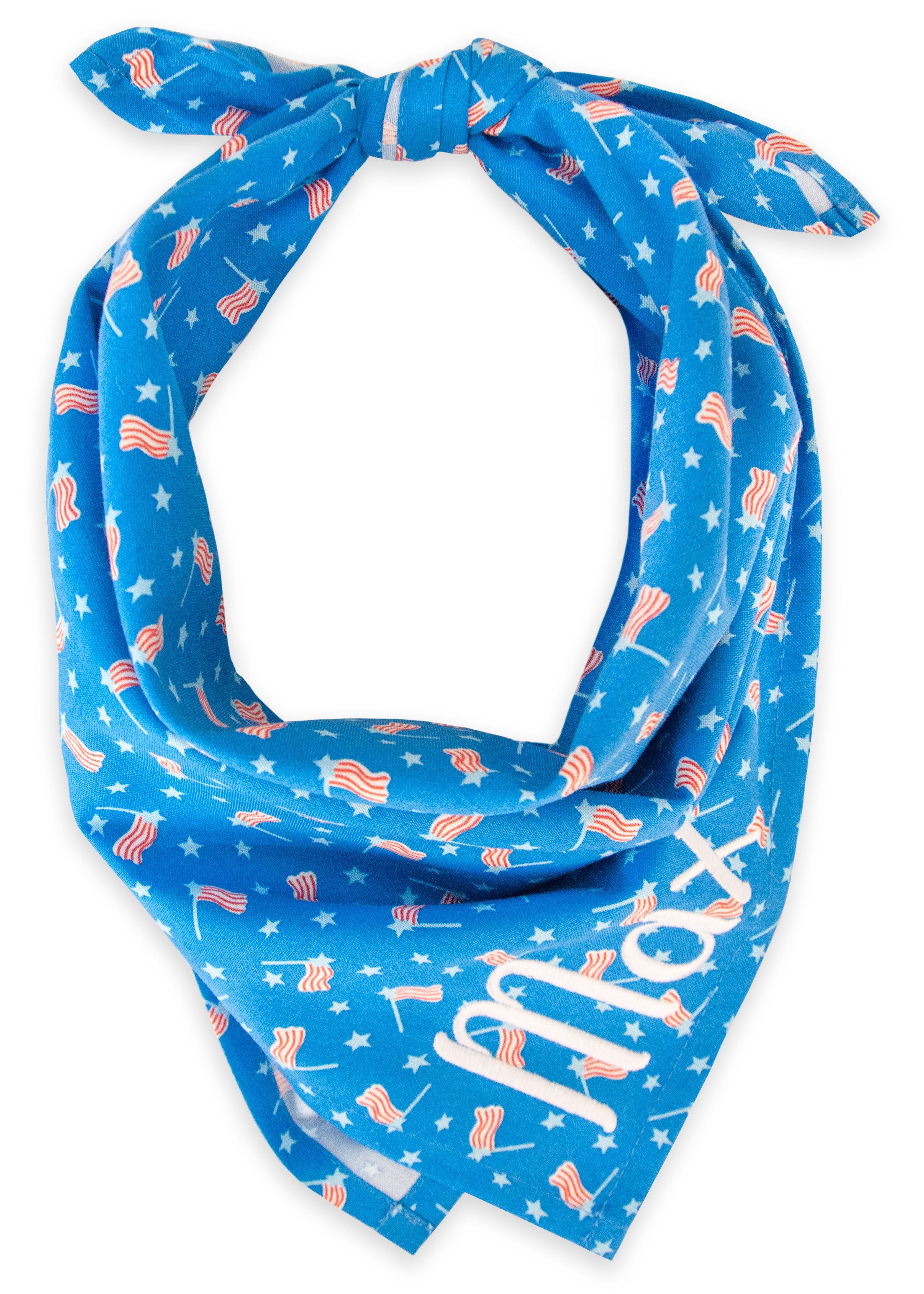 Festive dog bandana featuring a sky-blue background decorated with small stars and waving American flags, tied at the top. The name “Max” is stitched near the point of the bandana in bright white letters for a personalized touch.