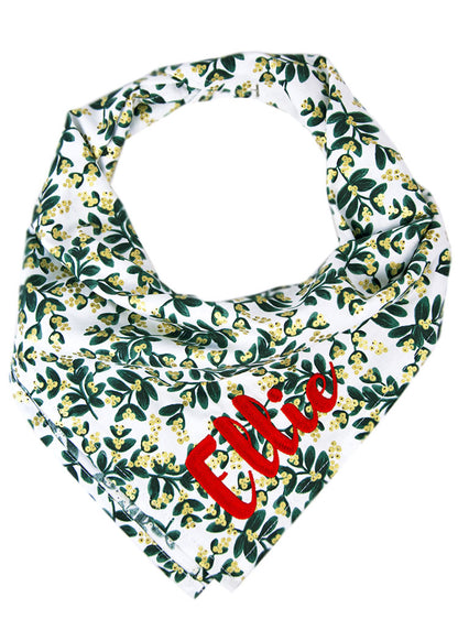 Holiday-themed dog bandana with a mistletoe print and bright custom name embroidery, blending seasonal charm with a personal flair for stylish pups.