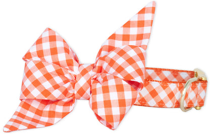Orange plaid dog collar featuring a large feminine double-layer bow in matching plaid fabric, with floppy tails that give it extra flair. The bright checkered print and gold hardware make it a standout pick for dogs with big personality and even bigger style.