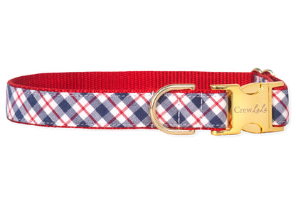 A stylish dog collar with a patriotic plaid design in navy, red, and white, finished with red webbing on the inside. It has a polished gold metal buckle engraved with “Crew LaLa” and a matching D-ring for functionality.