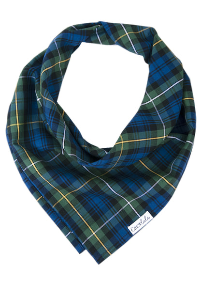 A classic dog bandana in green and navy tartan plaid with light colored accents, folded in a triangle style for a timeless preppy look.